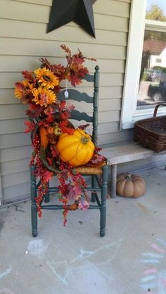 a chair with fall foliage and pumpkins sitting on the porch next to a star