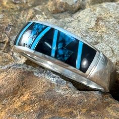 This beautiful Sterling Silver Ring, as part of the Shadow Peak Collection, features Ithica Peak Turquoise, Kingman Turquoise and Black Jade. Ring Width: 1/4"; Shank Width: 1/8" The ring is designed by David Rosales, one of the finest contemporary Southwest Artists in the world. He is the founder and co-owner of Supersmiths, Inc. of Gallup, NM. Each ring is custom made and carries a lifetime guarantee. . Southwestern Style Rings With Inlay, Southwestern Round Rings With Inlay, Blue Turquoise Ring With Inlay, Southwestern Inlay Jewelry For Anniversary, Southwestern Style Inlay Jewelry For Anniversary, Turquoise Inlay Round Rings, Blue Inlay Rings For Anniversary, Artisan Rings With Inlay For Anniversary, Turquoise Inlay Ring Gift