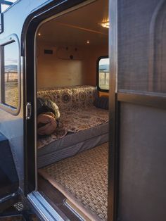 the interior of a camper van with its door open and bed in the back