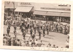 an old black and white photo of people marching down the street