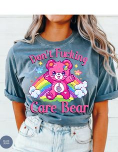 Indulge in rebellious comfort with our "I Don't Care Bear Vibes" T-shirt! This whimsical tee features a cheeky care bear boldly expressing your carefree attitude with a pair of unmistakable middle fingers and a vibrant rainbow backdrop. Crafted from soft, breathable fabric, this shirt guarantees both style and comfort. Embrace the carefree spirit and make a statement with this playful addition to your wardrobe. It's not just a shirt; it's an expression of your "don't give a care" attitude! *Unisex Sizing* Trendy Crew Neck T-shirt With Bear Print, Playful Cotton Tops With Bear Print, Cute Bear Print Crew Neck T-shirt, Trendy Short Sleeve T-shirt With Bear Print, Graphic Tee With Bear Print For Streetwear, Casual Bear Print T-shirt For Streetwear, Graphic Tee With Bear Print And Crew Neck, Rainbow Backdrop, Middle Fingers