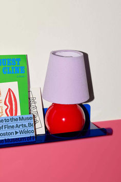 a red lamp sitting on top of a table next to a book and a box