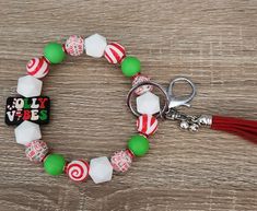 a green and white beaded bracelet with red tassel