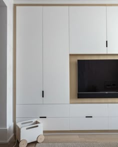 a living room with white cupboards and a flat screen tv mounted on the wall