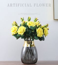 a vase with yellow roses in it sitting on a table next to a framed photograph