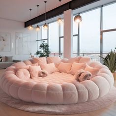 a living room with large windows and a round couch in the middle of it on top of a rug