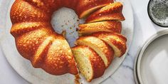 a bundt cake with slices cut out on a white plate next to silver dishes