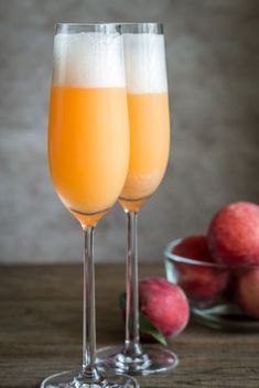 two wine glasses filled with champagne sitting next to apples