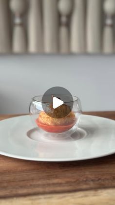 a white plate topped with food on top of a wooden table next to a vase