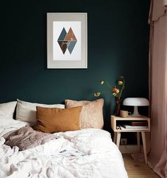 a bedroom with green walls, white bedding and pink curtains on the window sill