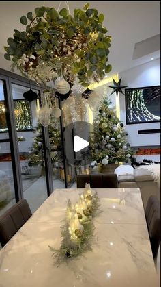 a dining room table with christmas decorations and lights hanging from it's centerpiece