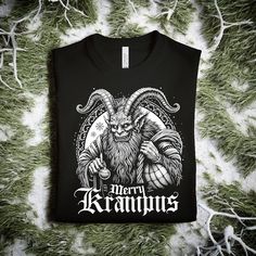 alternative Christmas / Horror T-Shirt / Gift Under 25 / Merry Krampus Christmas Shirt / Unisex black tee / Christmas Party / Happy New Year / alternative Christmas / Horror T-Shirt / Pagan T-Shirt ORDER BY DECEMBER 15TH FOR DELIVERY BEFORE CHRISTMAS 🖤 Welcome to Deviant Ink!  Our "Merry Krampus" unisex tee is perfect for those who celebrate the festive season with a touch of darkness!  This t-shirt is pre-shrunk to give a consistent fit that feels soft and lightweight, with just the right amou Black Crew Neck T-shirt For Holidays, Black Winter Holiday T-shirt, Black Graphic Print T-shirt For Holiday, Black Crew Neck Top For New Year, Christmas Black Graphic Tee T-shirt, Festive Black T-shirt With Letter Print, New Year Black Crew Neck T-shirt, Black Graphic Tee For Christmas, Black Crew Neck Christmas T-shirt