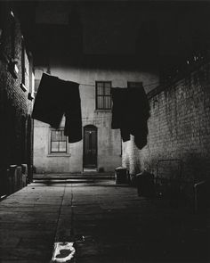 black and white photograph of clothes hanging out to dry in an alleyway at night