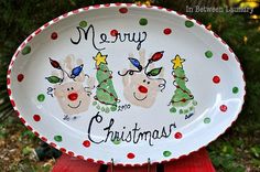 a merry christmas plate sitting on top of a wooden table next to some trees and bushes