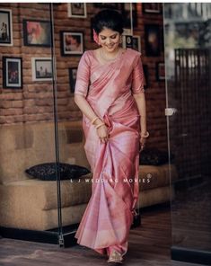 a woman in a pink sari walking into a room with pictures on the wall