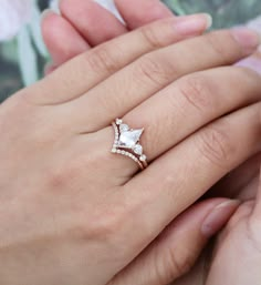 a woman's hand holding an engagement ring with two diamonds on top of it