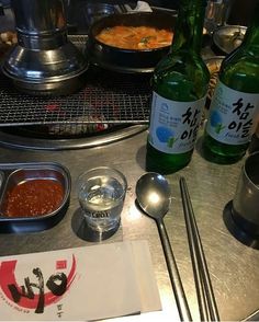 a table topped with bottles of beer and bowls filled with food next to utensils