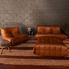 a living room with two leather couches and a coffee table in front of a brick wall