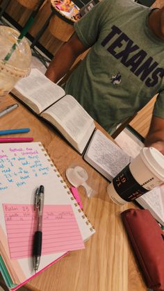 a person sitting at a table with notebooks and pens