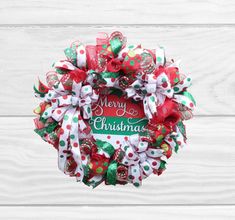 a christmas wreath hanging on the side of a white wooden wall with red and green decorations