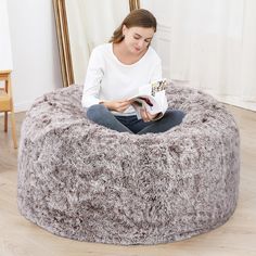 a woman sitting in a bean bag chair reading a book