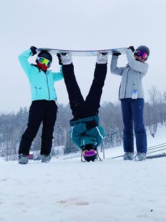 two snowboarders hold up their boards in the air