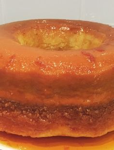 a close up of a bundt cake on a plate with orange sauce around it