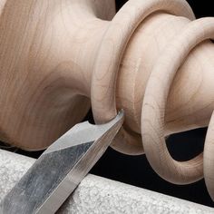 a pair of scissors sitting on top of a piece of wood next to a wooden sculpture