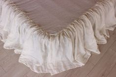 a bed with a white ruffled bedspread on it's bottom and side