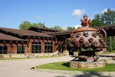 a large vase sitting on top of a lush green field in front of a building