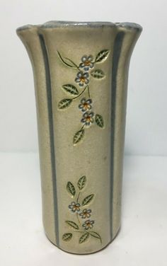 a white vase with blue and yellow flowers painted on the side is sitting on a table