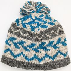 a blue and gray knitted hat with a pom - pom