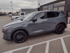 a gray mazda cx - 5 parked in front of a building with other cars