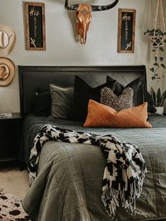 a bed room with a neatly made bed and two deer head mounted on the wall