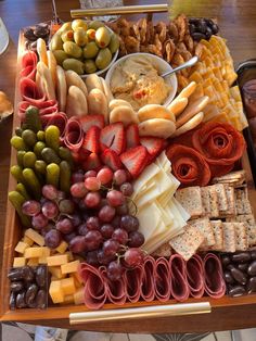 a platter filled with different types of cheeses, crackers, and fruit