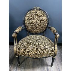 a leopard print upholstered chair against a blue wall with wooden floors and wood flooring