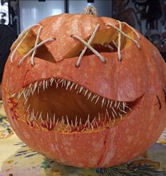 a carved pumpkin with sharp teeth and fangs on it's face, sitting on a table