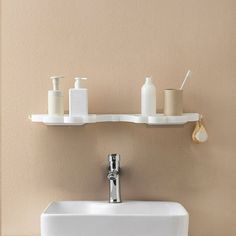 a bathroom sink with two shelves above it and soap dispensers on the wall