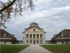 an old building with columns and pillars on the front is surrounded by green lawns