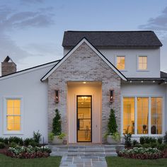 a white brick house with large windows at dusk