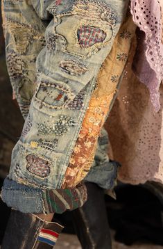 an old pair of jeans with patches and laces hanging from the back of it