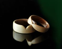 two wooden rings sitting on top of a black table next to each other with reflection