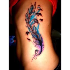 a woman's stomach with a blue and black feather tattoo on her lower back