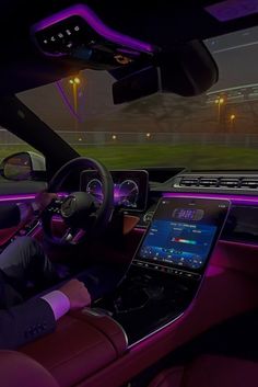 the interior of a car is lit up with purple lights and features electronic dashboard controls