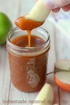 an apple being dipped with caramel sauce in a mason jar next to sliced apples