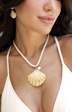 Online only! Make a bold statement with Ettika's Scallop Shell Pendant Necklace, showcasing a chunky white chain and a large seashell pendant adorned with a faux pearl. The gold finish adds a touch of luxury, perfect for any beach-inspired look.


	18k Gold Plated, Zinc, Silk Cord, Freshwater Pearl
	16" with 3" extender
	2" Scallop Shell Pendant
	Lobster Clasp Earrings Outfit, Scallop Shell, Back Necklace, Scallop Shells, Accessories Ideas, Silk Cord, Pearl Charms, Shell Earrings, Shell Pendant