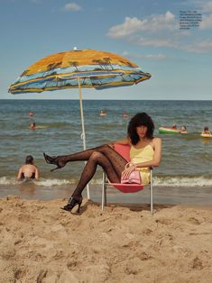 a woman sitting in a chair on the beach