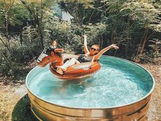 a man and woman are floating on an inflatable raft at the edge of a pool