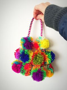 a person holding a colorful bag with pom - poms