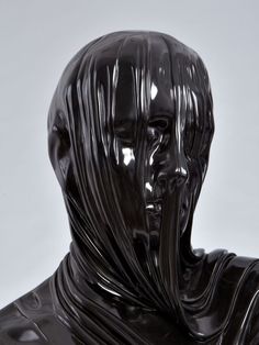 a black statue is shown in front of a white background with the image of a man's head wrapped around his neck